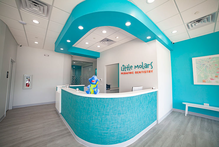 Little Molars front desk with the practice sign on a bright teal wall